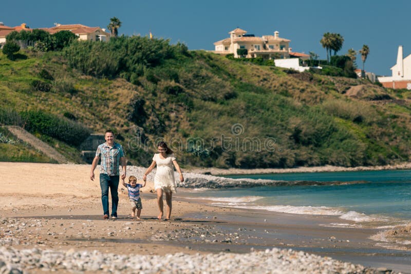 Famille heureuse marchant sur la côte en Espagne photographie stock libre de droits Famille heureuse marchant sur la côte en Espagne photographie stock libre de droits