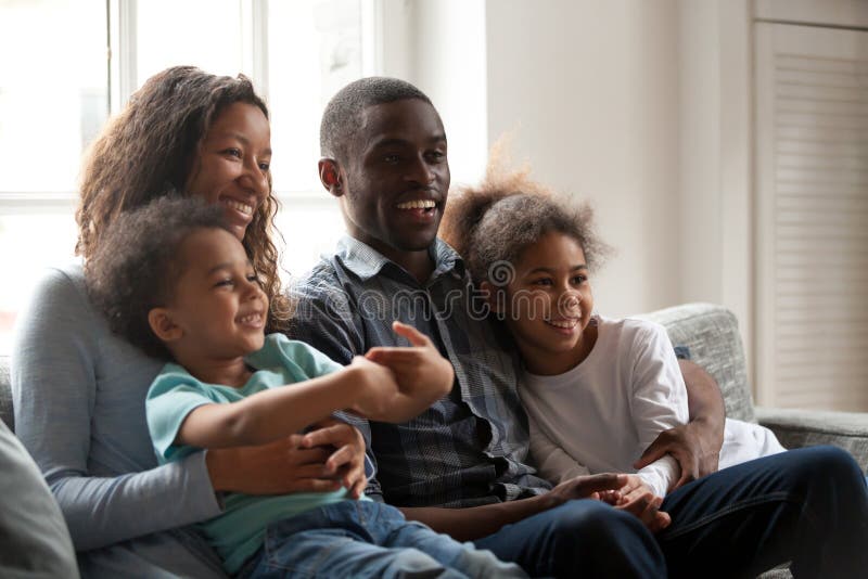 Famille heureuse noire s'asseyant ensemble sur le divan à la maison images stock Famille heureuse noire s'asseyant ensemble sur le divan à la maison images stock