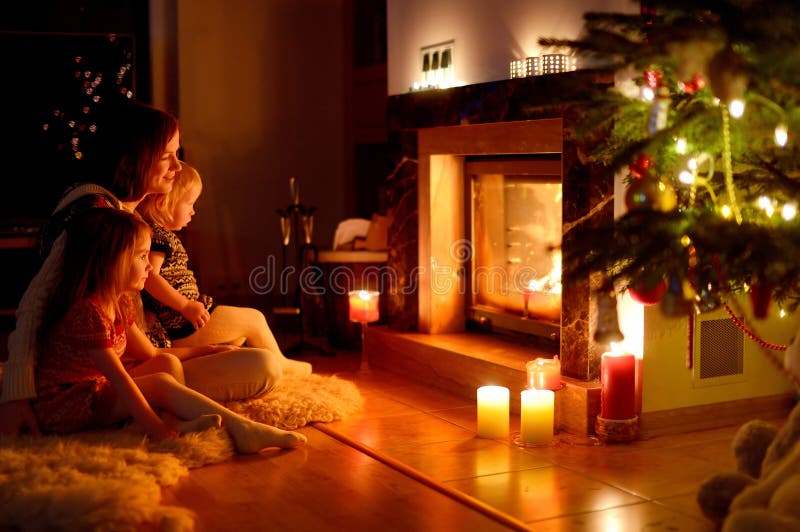 Famille heureuse par une cheminée sur Noël image libre de droits