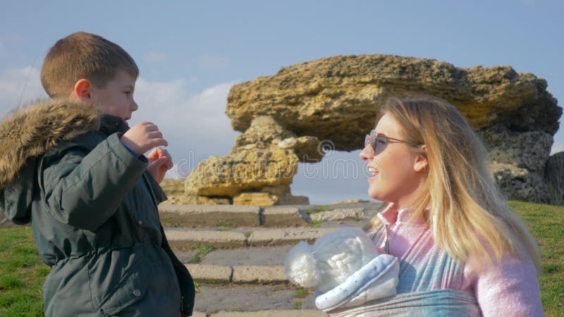 Famille heureuse, petit garçon parlant à la femme avec le bébé sur l'air ouvert au printemps