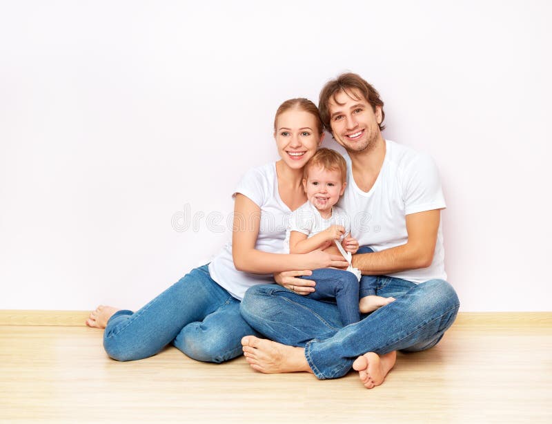 Famille heureuse sur le plancher près du mur vide dans l'appartement acheté sur l'hypothèque photographie stock libre de droits Famille heureuse sur le plancher près du mur vide dans l'appartement acheté sur l'hypothèque photographie stock libre de droits