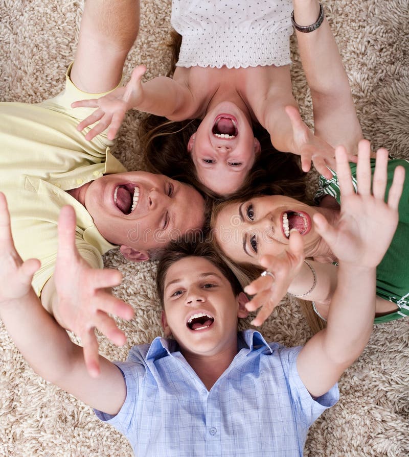 Portrait of happy family lying on carpet with their heads close together and shouting. Portrait of happy family lying on carpet with their heads close together and shouting