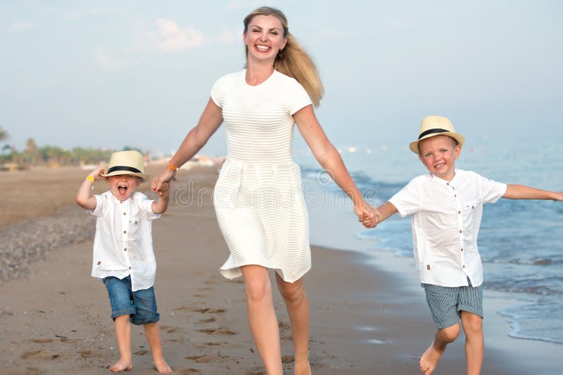 Famille marchant sur la plage de soirée pendant le coucher du soleil Mère et deux fils photos libres de droits Famille marchant sur la plage de soirée pendant le coucher du soleil Mère et deux fils photos libres de droits
