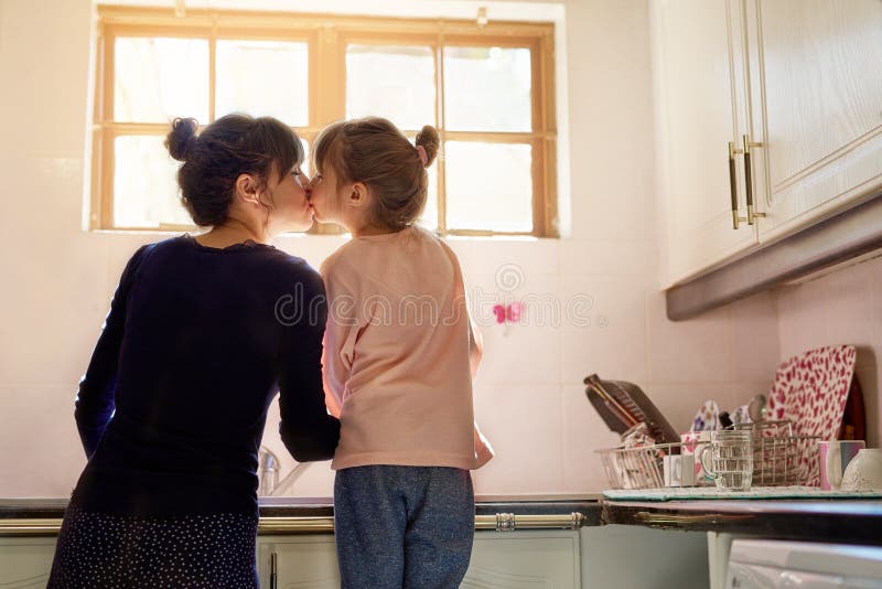 Famille mère et fille baiser dans la cuisine lave vaisselle pour aider à l'apprentissage et le développement des compétences de la photographie stock