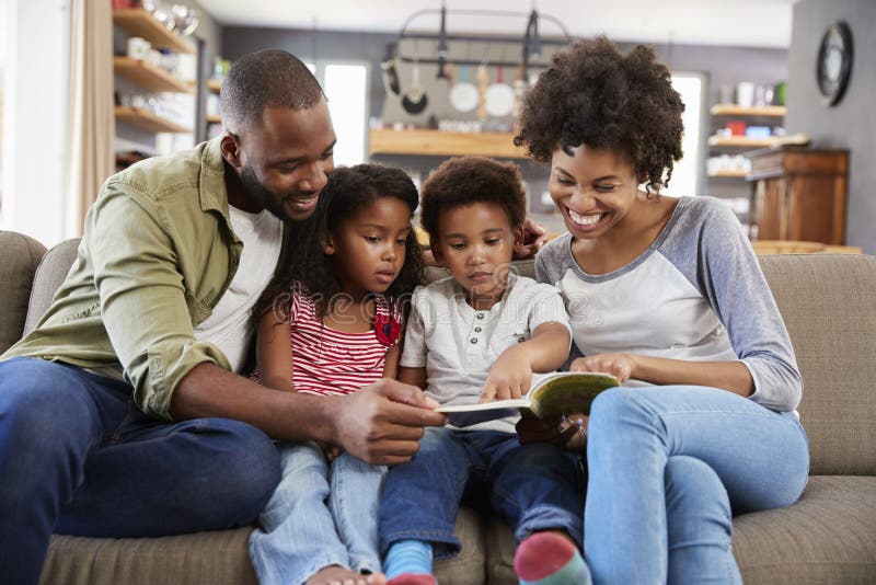 Famille s'asseyant sur Sofa In Lounge Reading Book ensemble photographie stock libre de droits Famille s'asseyant sur Sofa In Lounge Reading Book ensemble photographie stock libre de droits