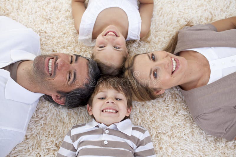 Smiling family lying on floor with heads together. Smiling family lying on floor with heads together