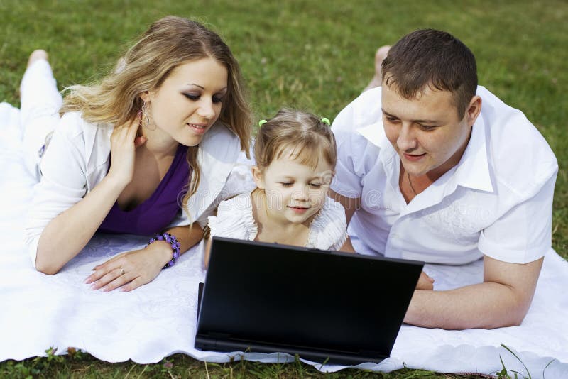 Famille sur le pique-nique avec l'ordinateur portatif