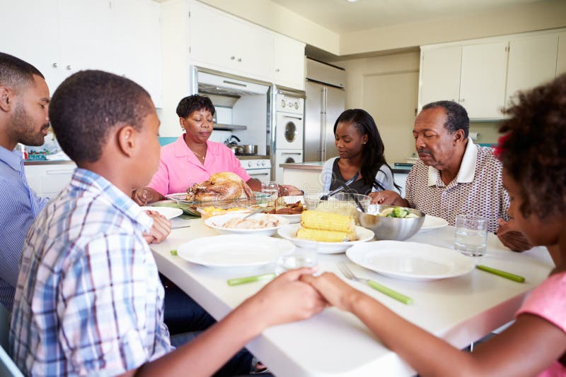 Famille sur plusieurs générations disant la prière avant de manger le repas