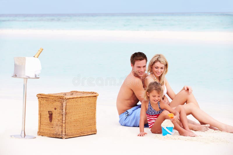 Family On Beach With Luxury Champagne Picnic Smiling