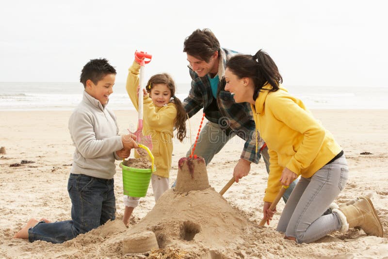 Famiglia, la Costruzione di castelli di sabbia Sulla Spiaggia d'Inverno sorridente.