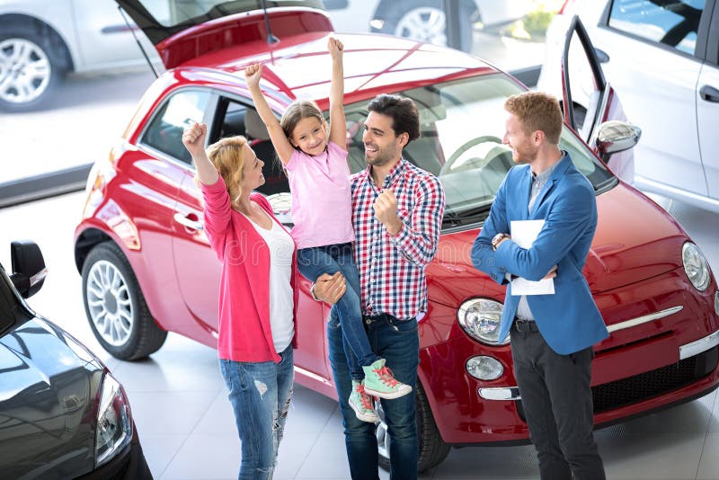 Happy family at the dealer buying a new car, excited with hands up. Happy family at the dealer buying a new car, excited with hands up