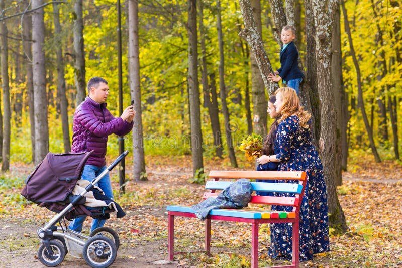 Family, childhood, season, technology and people concept - happy family photographing in autumn park stock image Family, childhood, season, technology and people concept - happy family photographing in autumn park stock image