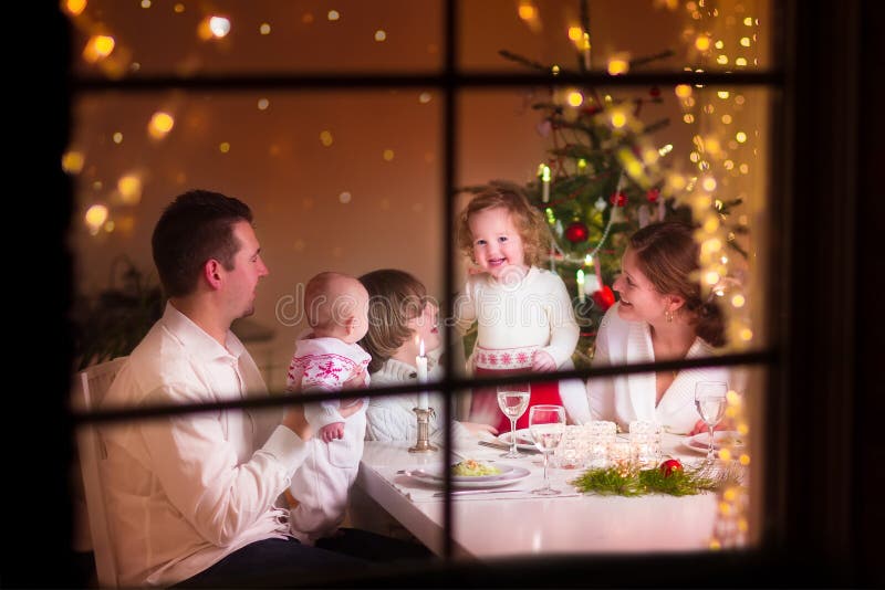 Joven el gran familia celebra feliz, afuera través de decorado sala de estar un árbol vela las luces, feliz padres comer tres.