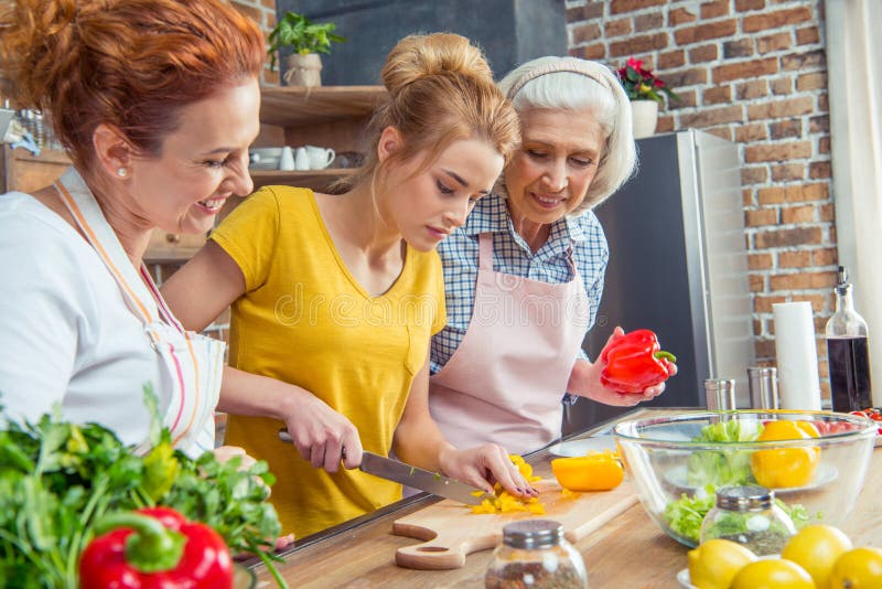 Happy three-generation family cooking together vegetable salad