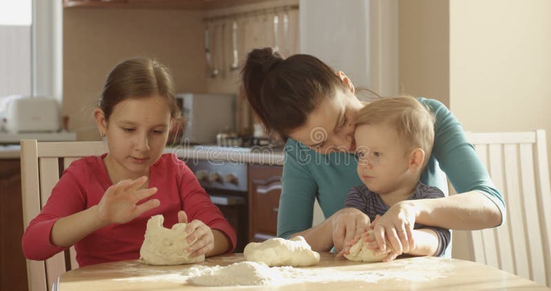 Family Cooking Together Kneading Dough in the Kitchen with Mother Daughter and Son on Sunny Day
