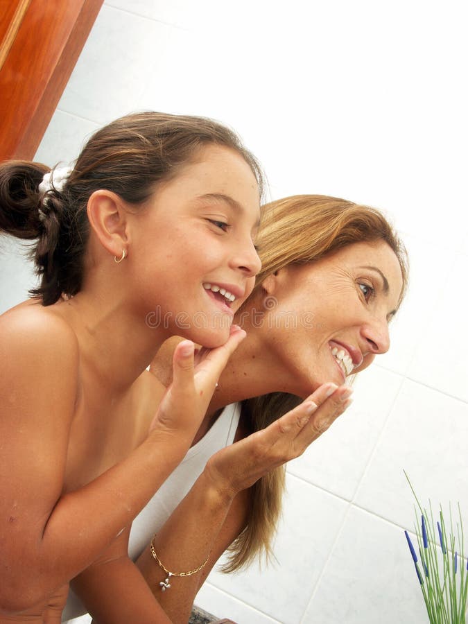 Mother and daughter appliying face cream.