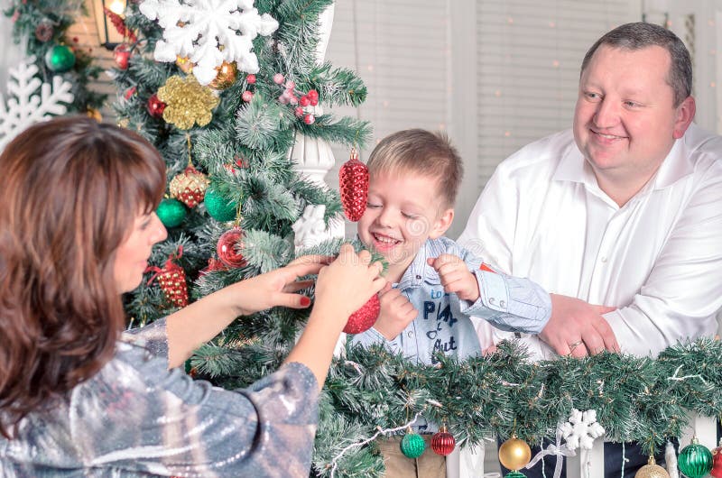 Family decorating a Christmas tree with boubles in the living-room stock images Family decorating a Christmas tree with boubles in the living-room stock images