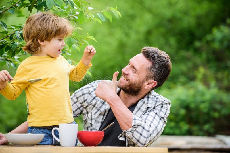 Family dinner time. father and son eating outdoor. happy fathers day. Little boy with dad eat cereal. summer picnic. Morning breakfast. healthy food and dieting. Childrens day. Happy family together.