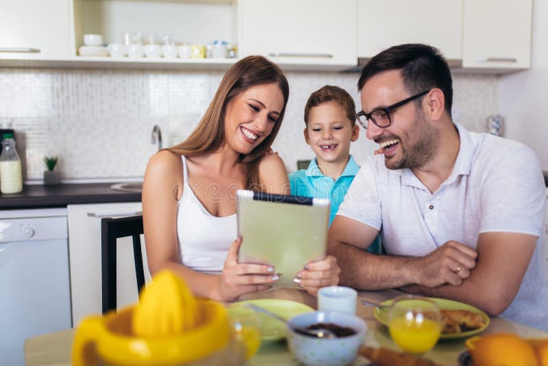 Family eating breakfast at kitchen table using digital tablet stock images Family eating breakfast at kitchen table using digital tablet stock images