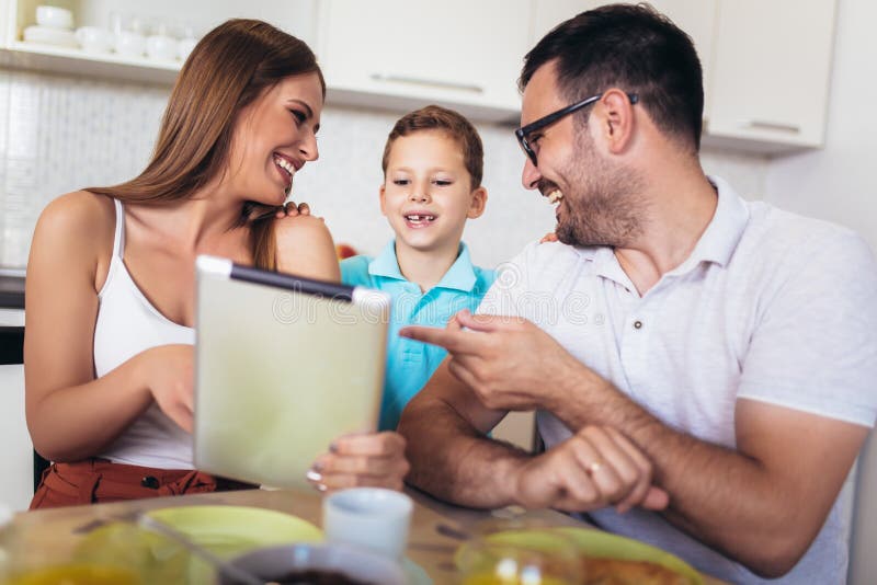 Family eating breakfast at kitchen table using digital tablet stock photography Family eating breakfast at kitchen table using digital tablet stock photography