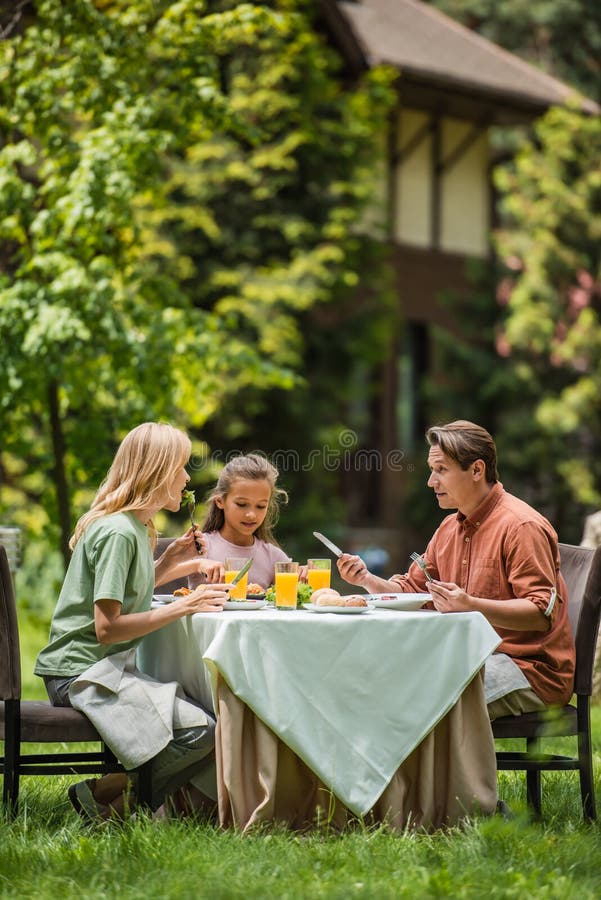 Family eating tasty food near orange