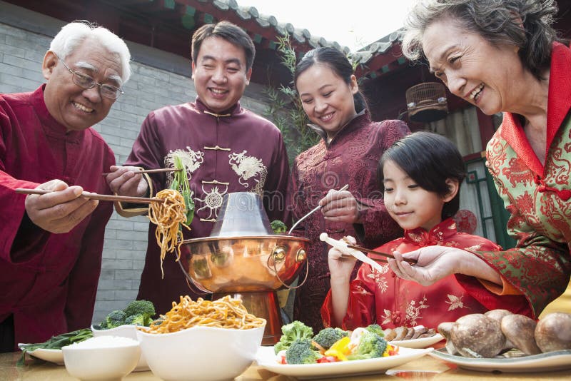Family enjoying Chinese meal in traditional Chinese clothing royalty free stock photo Family enjoying Chinese meal in traditional Chinese clothing royalty free stock photo