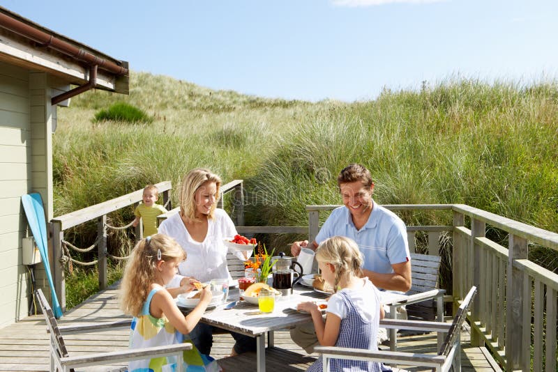 Familia feliz comida sobre el cubierta de ellos refugio de montana.