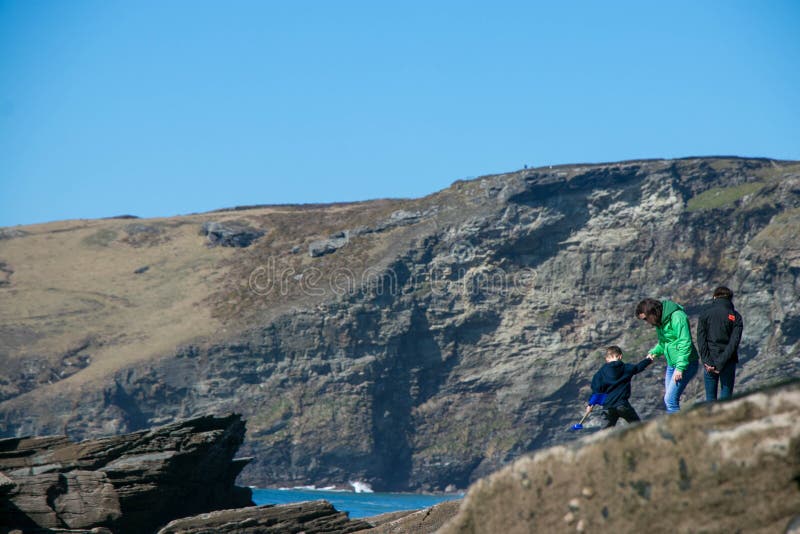Family of father, mother, child with their backs to camera make their away across rocks to the ocean royalty free stock images Family of father, mother, child with their backs to camera make their away across rocks to the ocean royalty free stock images