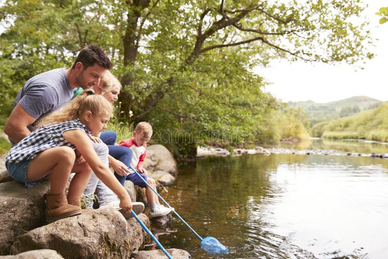 Family Fishing With Nets In River In UK Lake District.