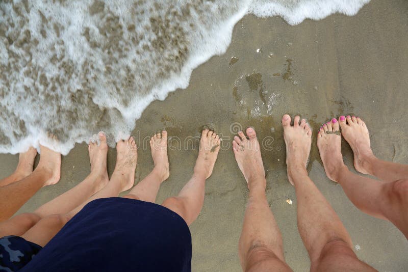 Family of five barefoot people on the sand by the sea royalty free stock image