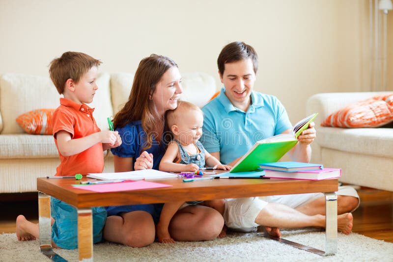 Family of four reading and drawing together at home. Family of four reading and drawing together at home