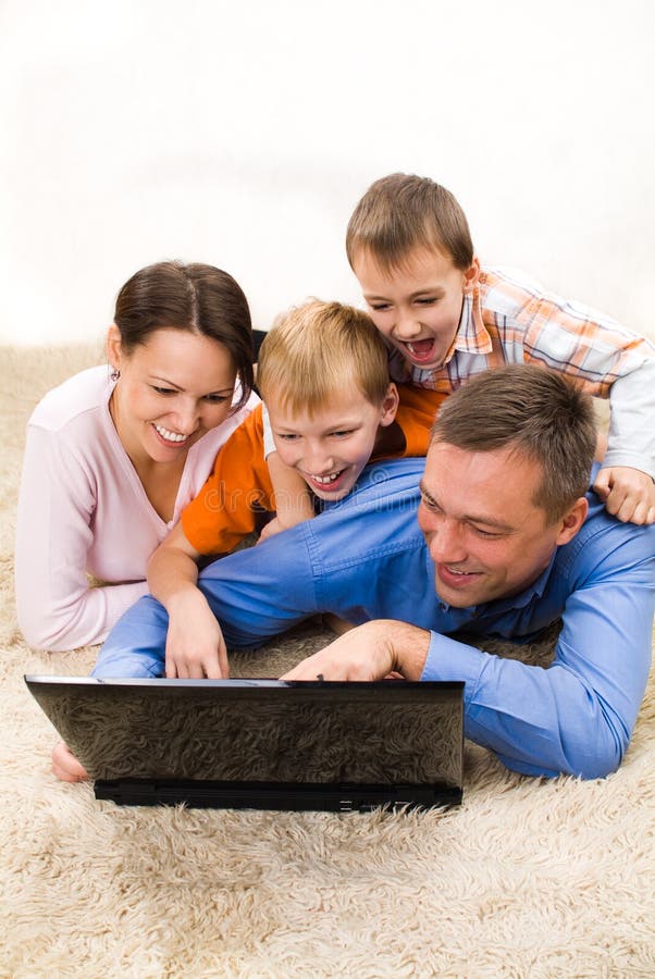 Family of four lying and looking at laptop