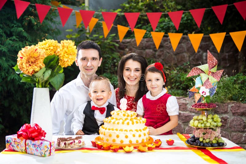 Family of four people father mom son and daughter celebrates daughter`s birthday three years sitting at a festive decorated table stock image Family of four people father mom son and daughter celebrates daughter`s birthday three years sitting at a festive decorated table stock image
