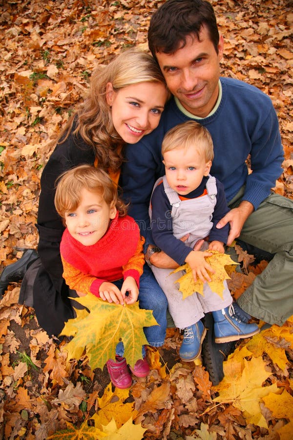 Family of four with yellow maple leaves in wood