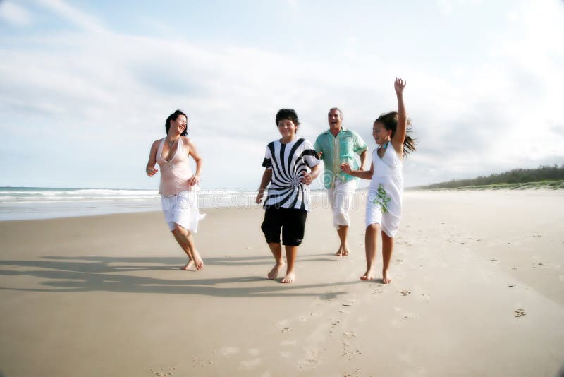 Caucásico blanco familia de cuatro divirtiéndose común correr sobre el Playa.