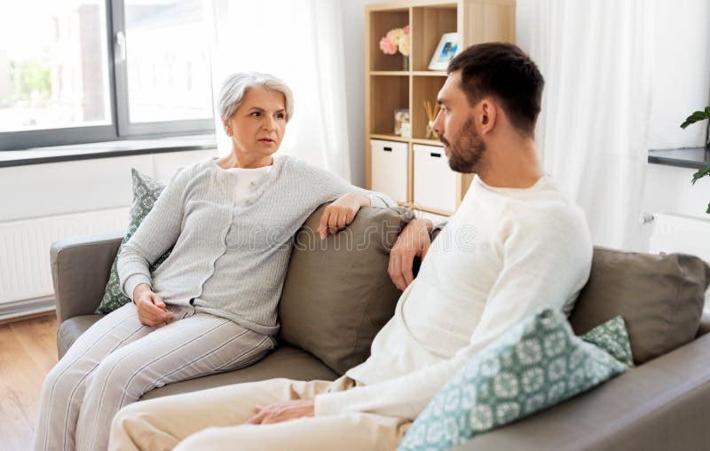 Senior mother talking to adult son at home