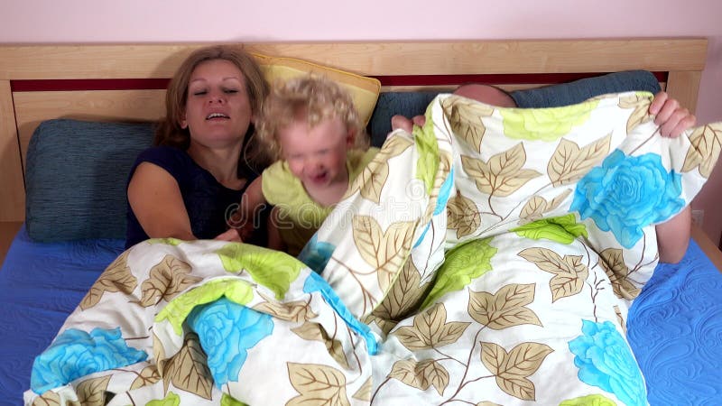 family with girl play hide under wrap on bed. Parenthood. 4K