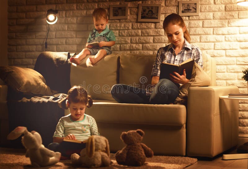 Rodina pred bežný na posteľ matka a čítať knihy a hrať okolo lampa v.