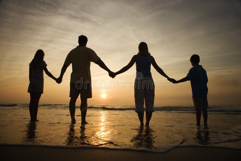 Silueta de familia posesión manos sobre el Playa seguimiento atardecer.