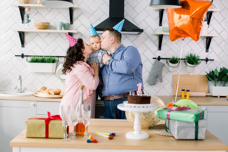 Family, holidays and people concept - mother, father and happy little son at home birthday party, parents are kissing