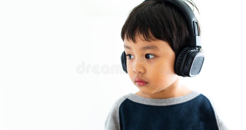 Family, home, technology and music concept. Portrait Young little Asian boy listening music with headphones at home. School child royalty free stock photo Family, home, technology and music concept. Portrait Young little Asian boy listening music with headphones at home. School child royalty free stock photo