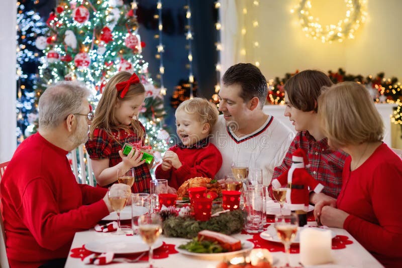 Family with kids having Christmas dinner at tree