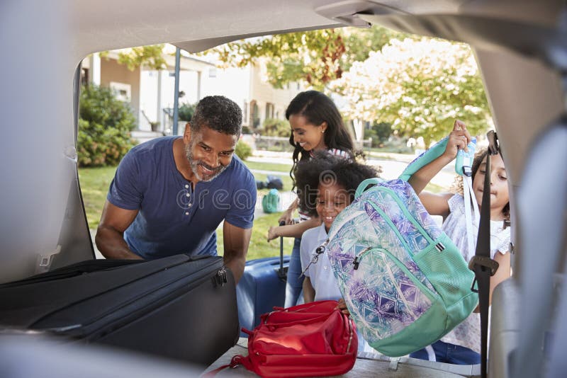 Family Leaving For Vacation Loading Luggage Into Car