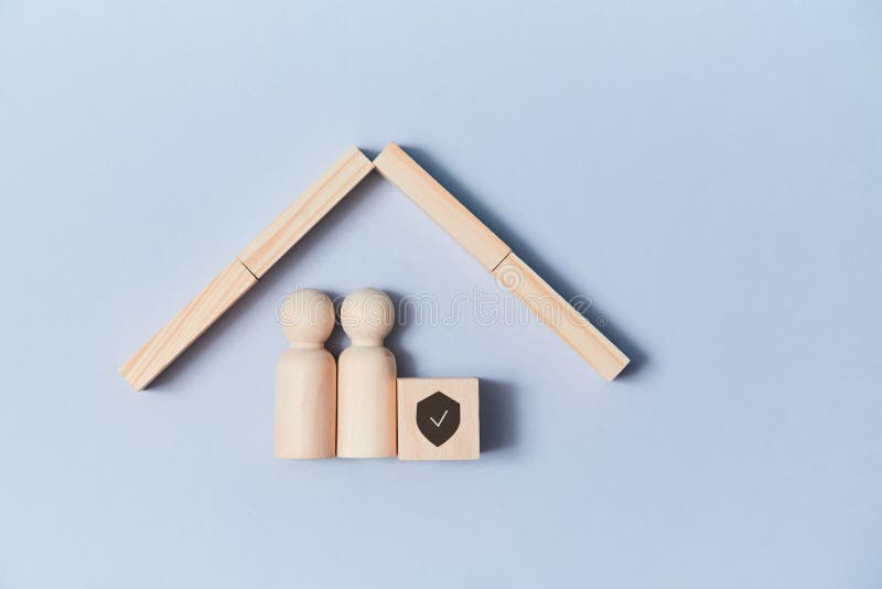 Family life and property insurance. Wooden figures family under house roof. Home building. Copy space. Isolated on blue.