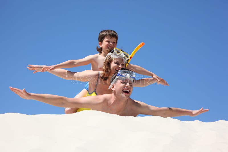 Family lying on sand with hands up