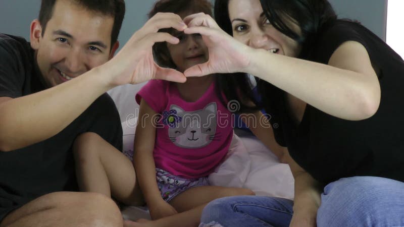 Family making heart symbol from hands to their girl