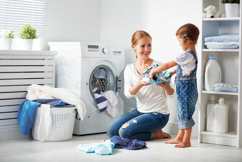 Family mother and child girl in laundry room near washing machi stock photos Family mother and child girl in laundry room near washing machi stock photos