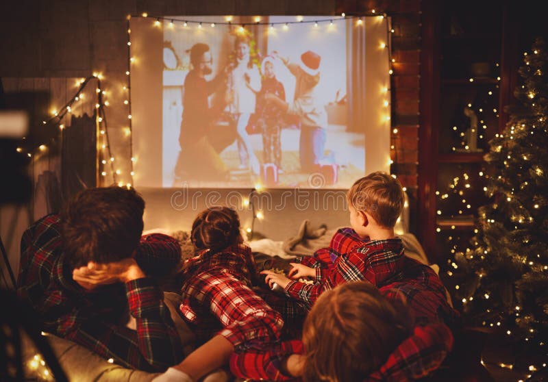 Family mother father and children watching projector, TV, movies with popcorn in   christmas evening   at home