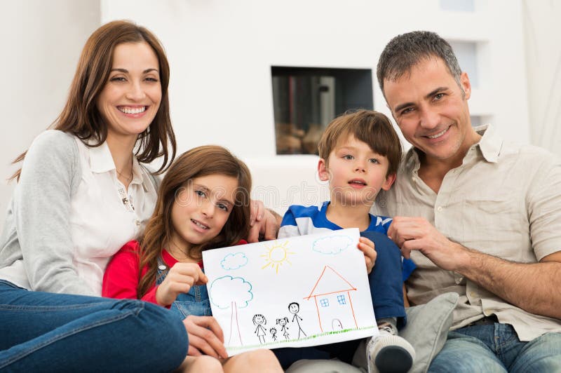 Smiling Parents With Children Sitting On Couch Showing Together Drawing of a new Home. Smiling Parents With Children Sitting On Couch Showing Together Drawing of a new Home