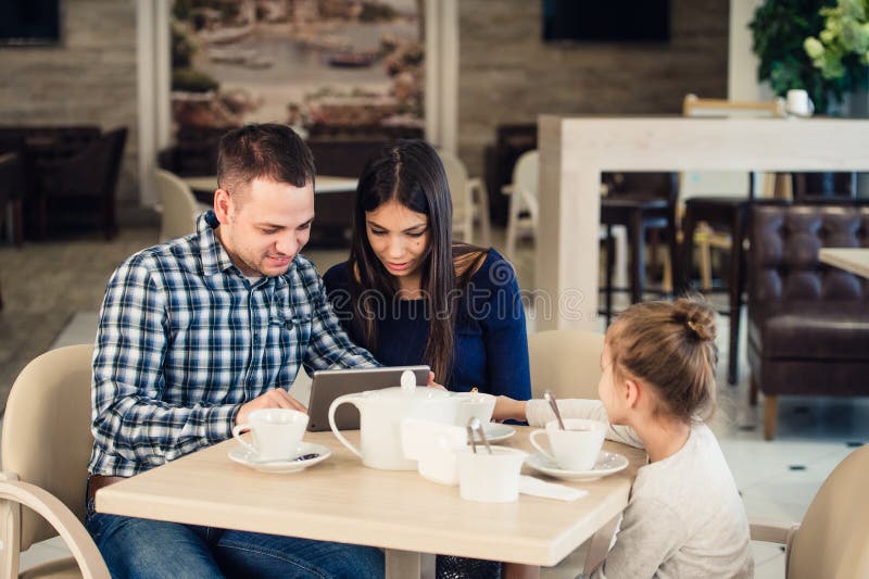 Family, parenthood, technology people concept - happy mother, father and little girl with tablet pc computer having